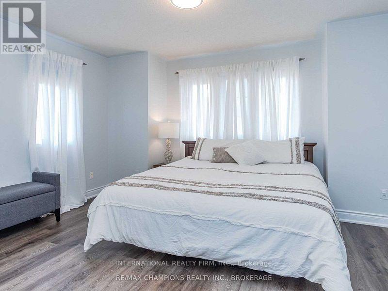 A bedroom with a large bed and a grey sofa.