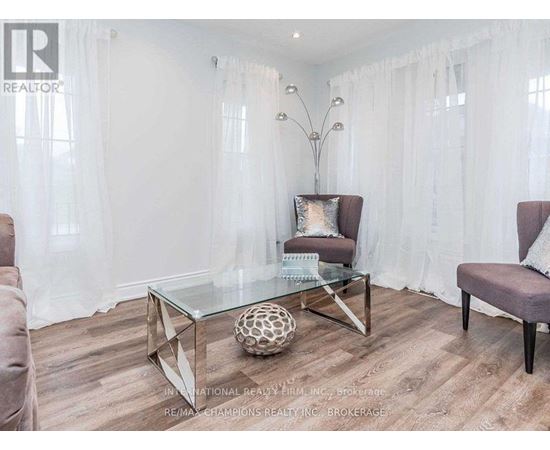 A modern living room with a glass coffee table and two chairs.