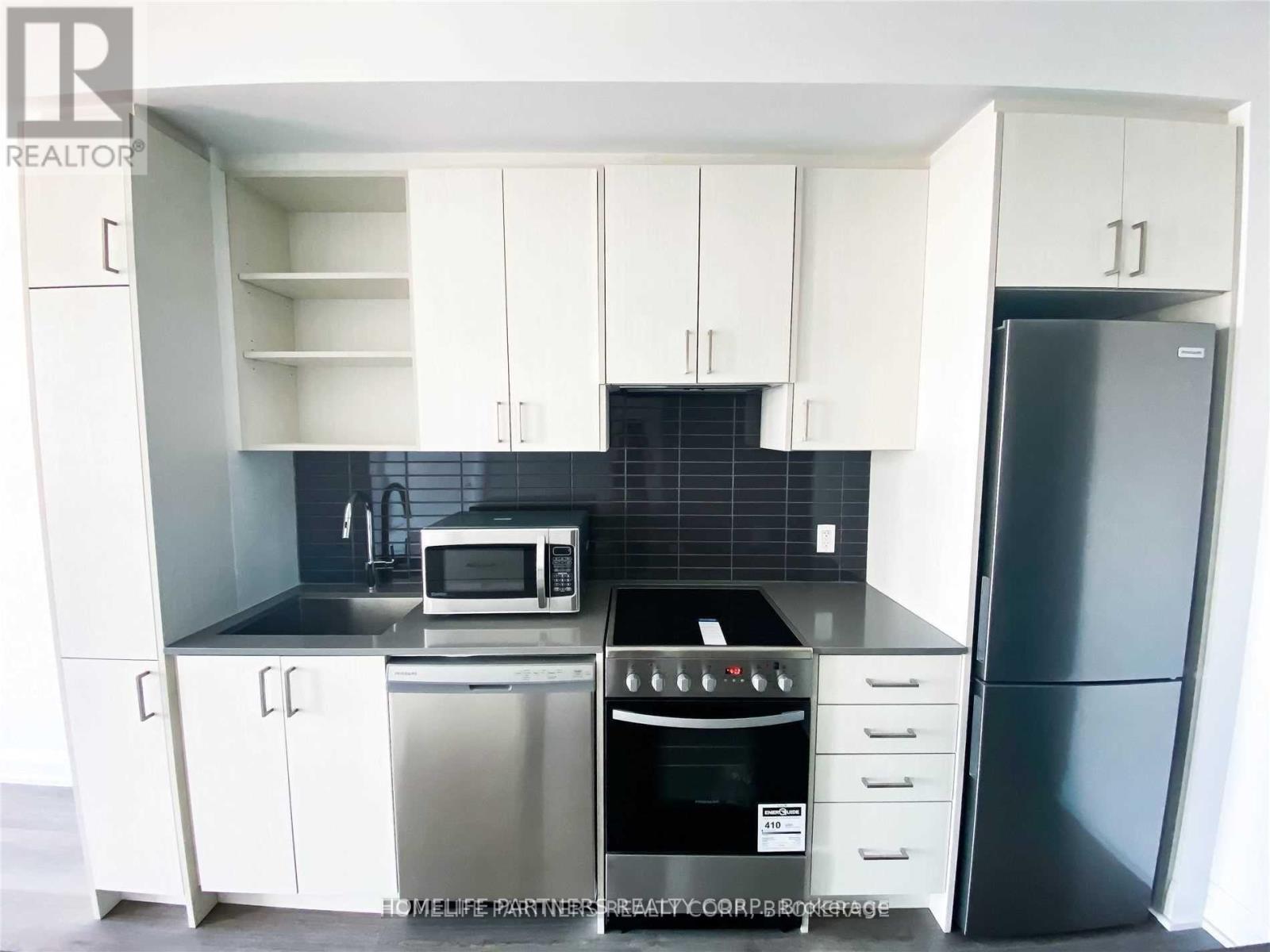 A kitchen with white cabinets and a black countertop.