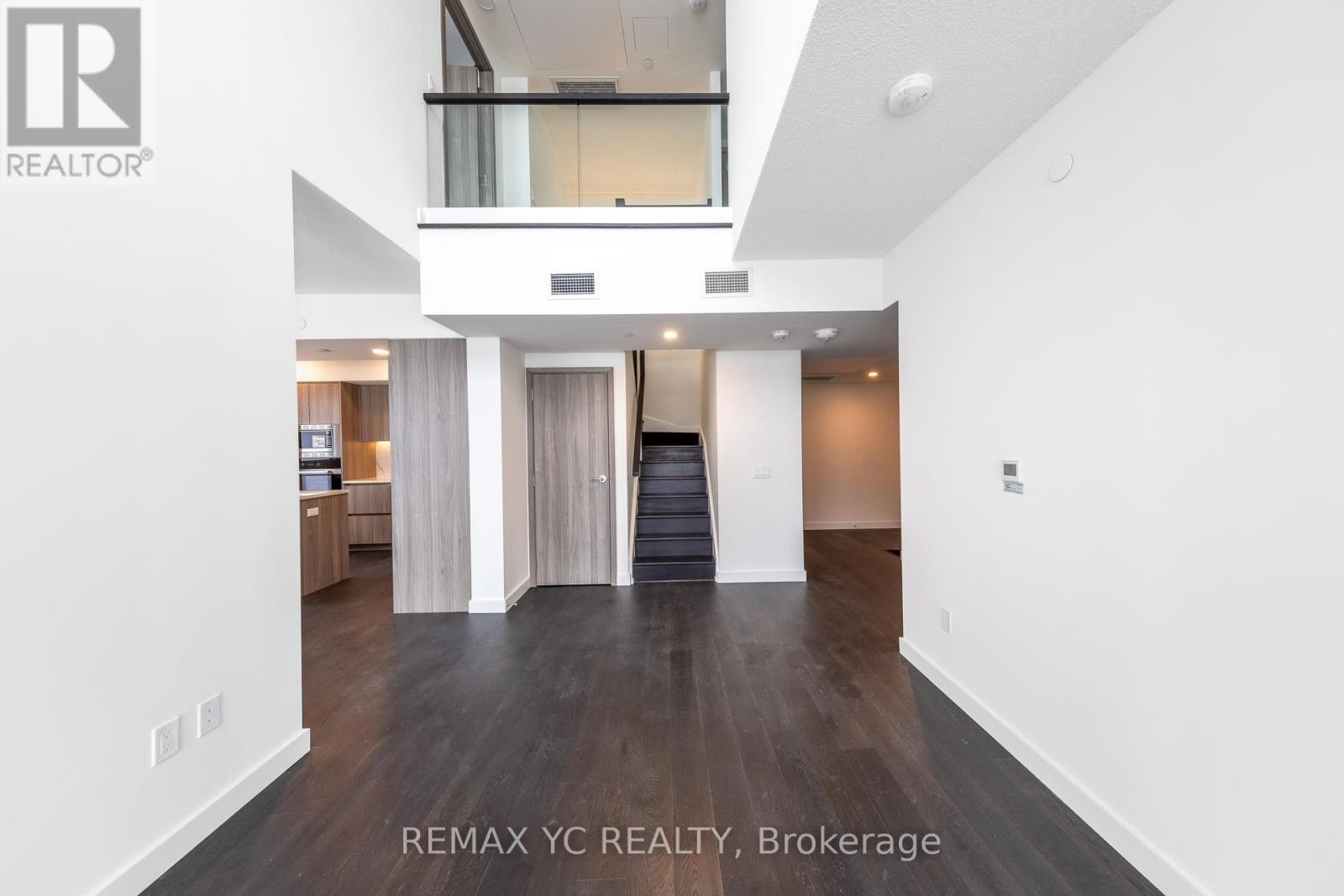 A spacious, empty living room with a staircase leading to the upper level.