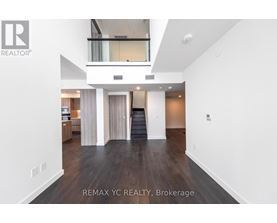 A spacious, empty living room with a staircase leading to the upper level.