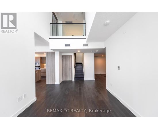 A spacious, empty living room with a staircase leading to the upper level.