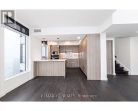 A spacious, well-lit room with a kitchen area and a staircase.