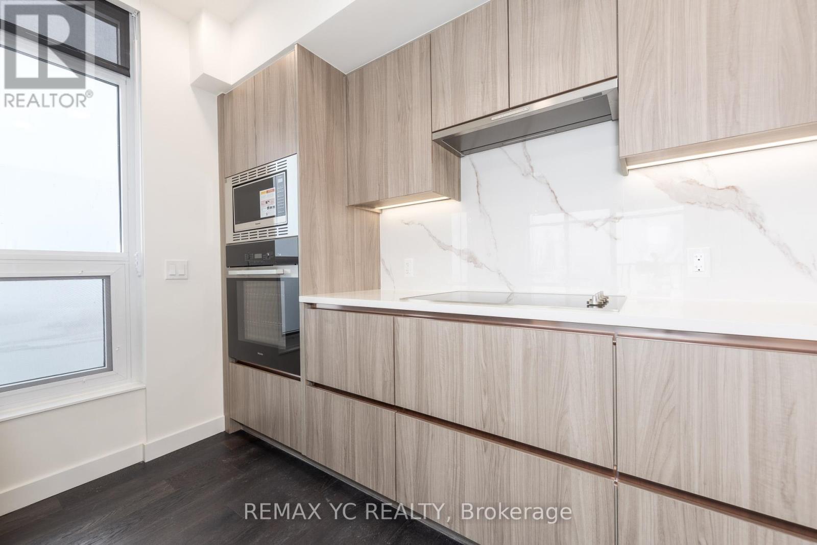 A modern kitchen with wooden cabinets and a marble backsplash.
