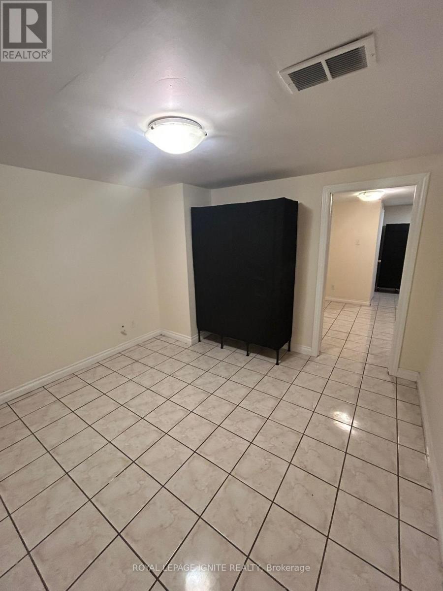 A room with a black refrigerator and white tiled flooring.