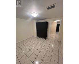 A room with a black refrigerator and white tiled flooring.