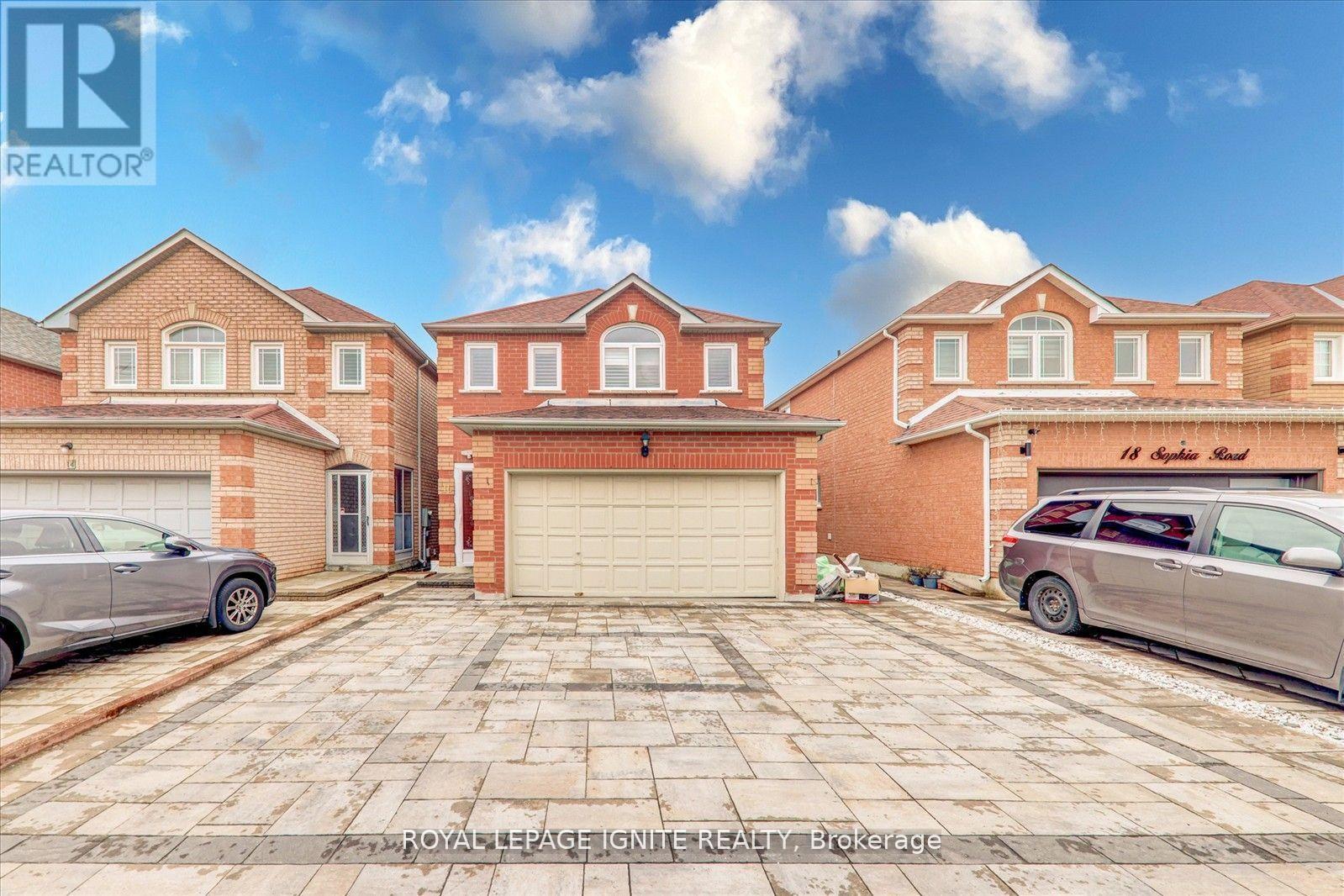 A large brick house with a garage and two cars parked in front.