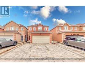 A large brick house with a garage and two cars parked in front.