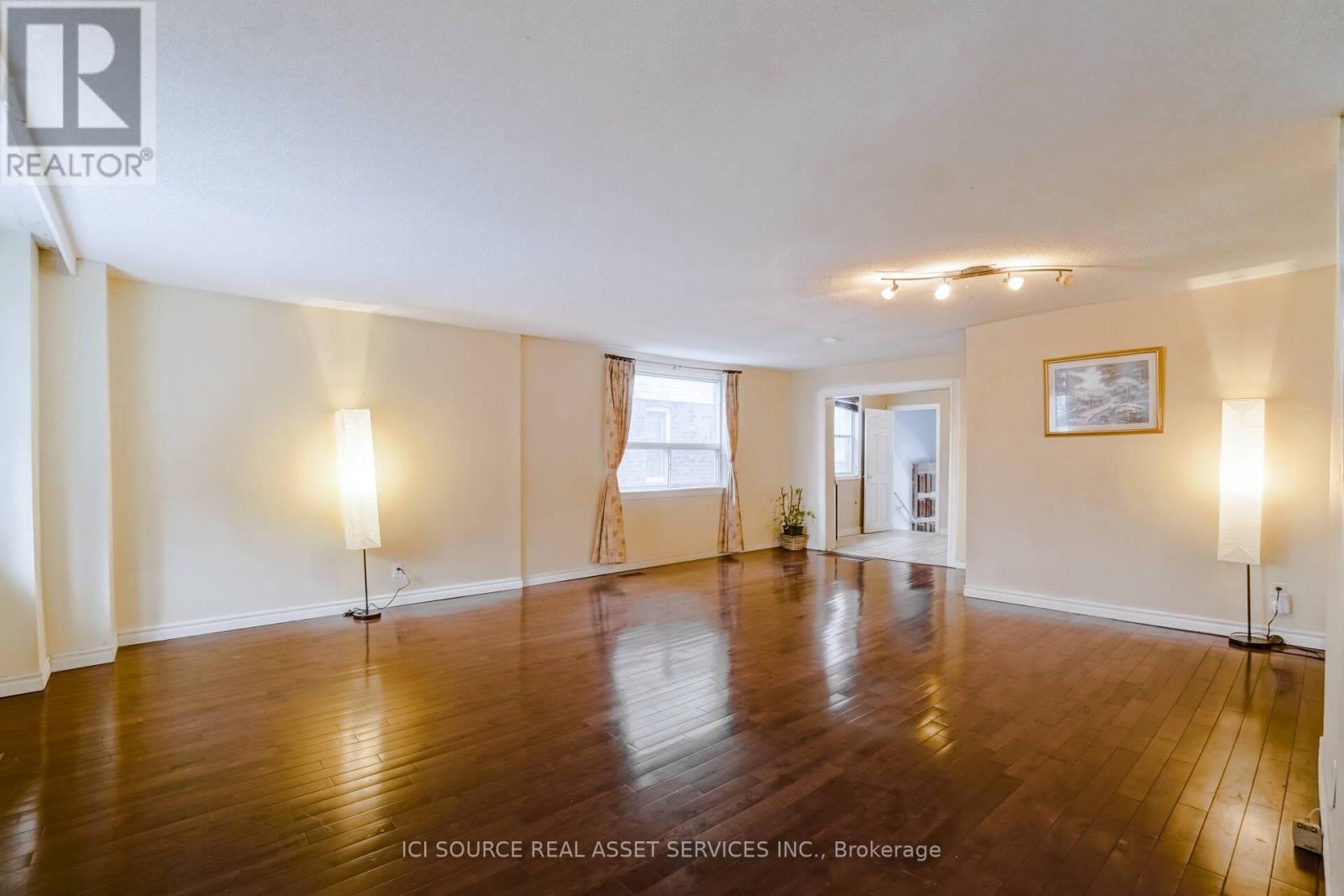 A large empty room with wooden floors and white walls.