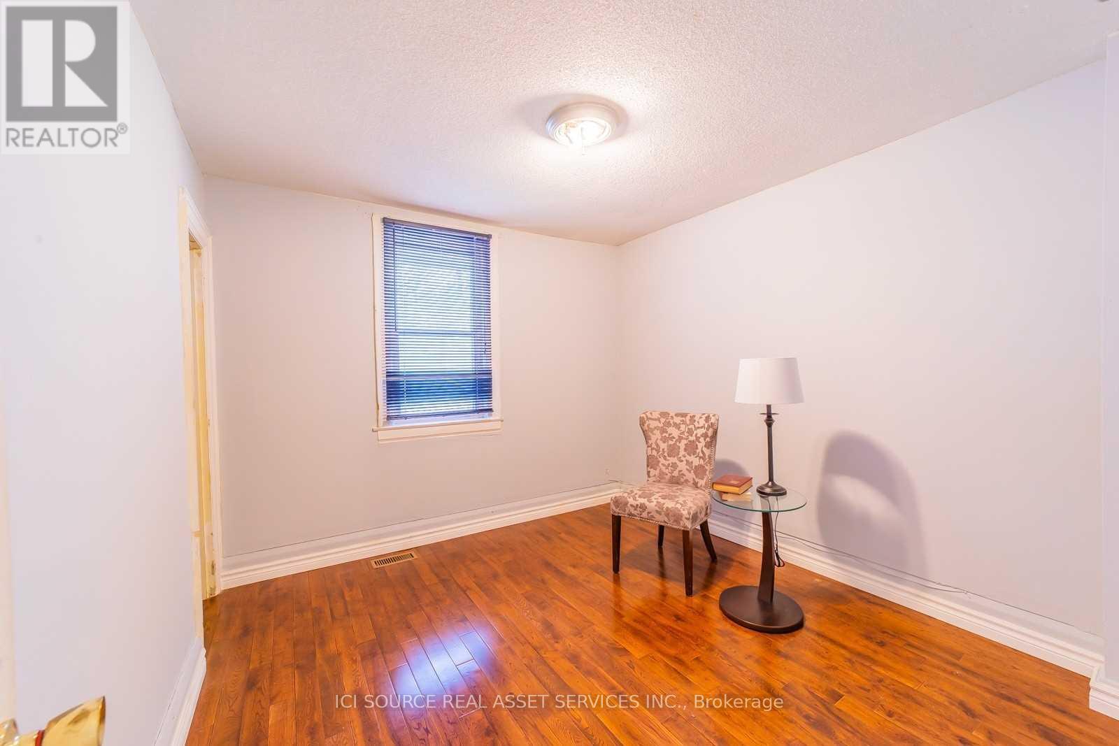 A room with a wooden floor, a chair, and a lamp.
