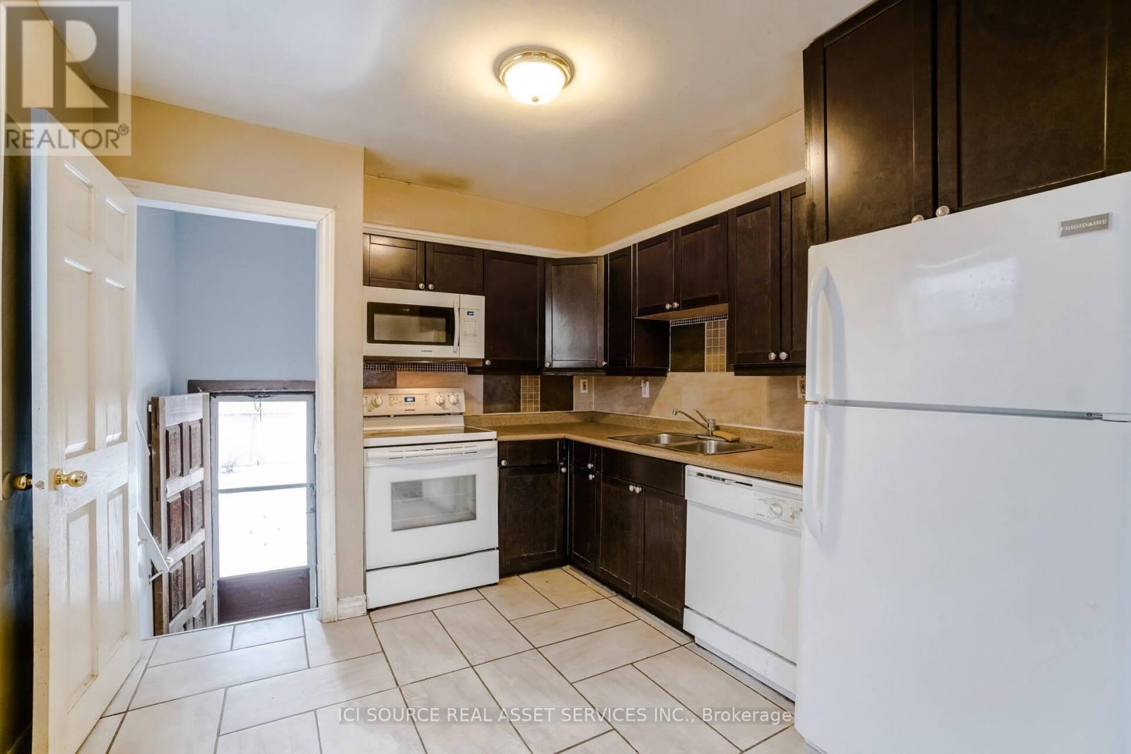 A kitchen with white appliances and black cabinets.