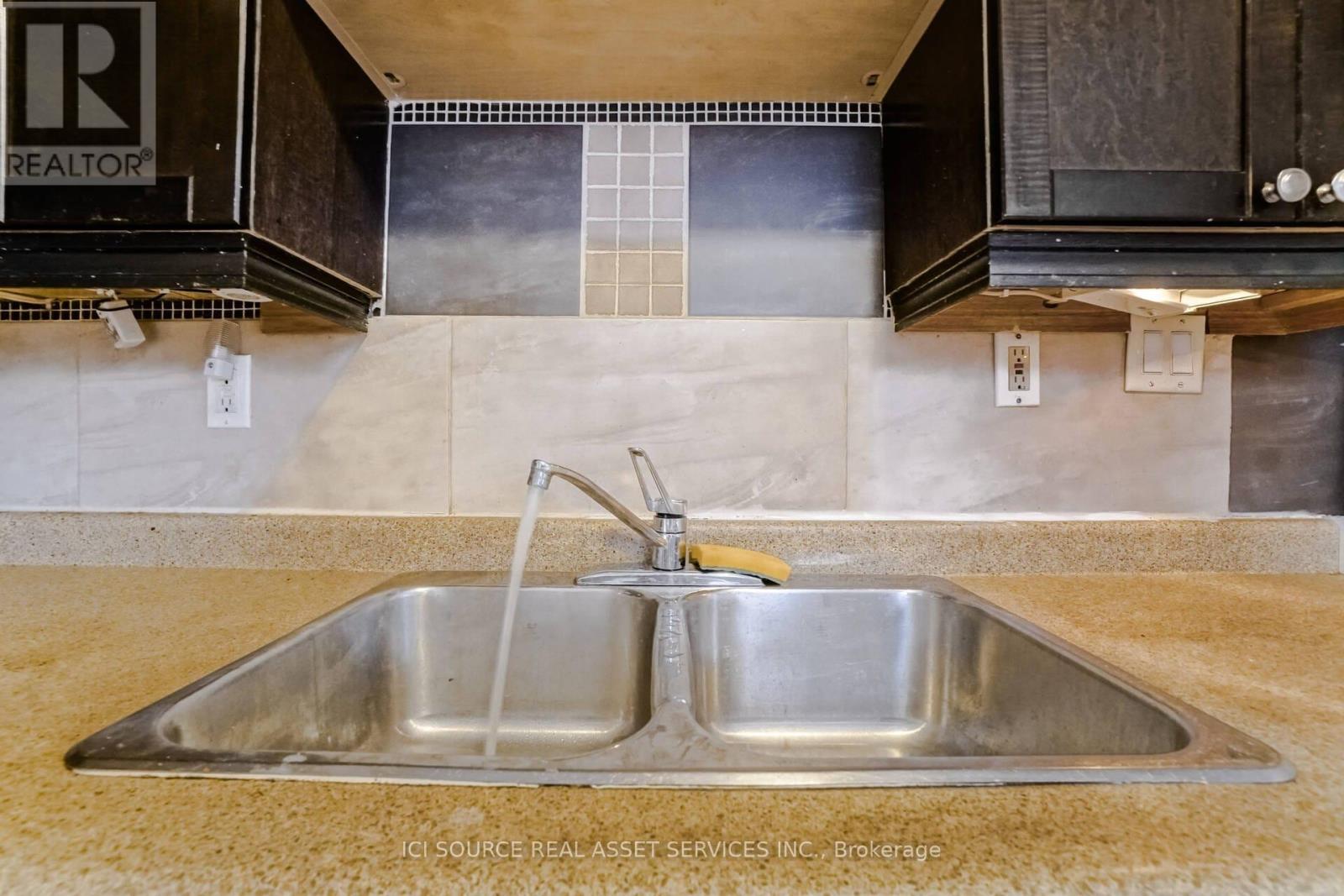A kitchen sink with a faucet and a tile backsplash.