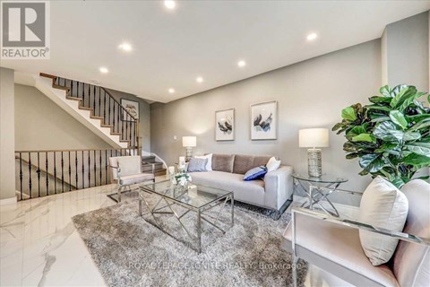 A living room with a glass coffee table and a staircase.