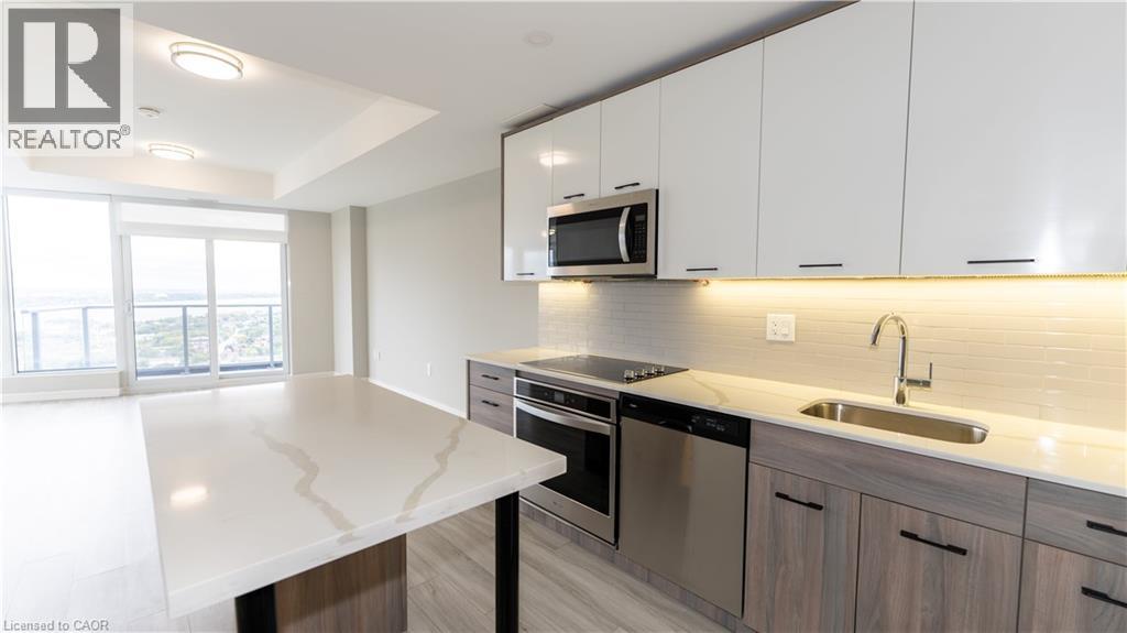 A modern kitchen with a white countertop and stainless steel appliances.