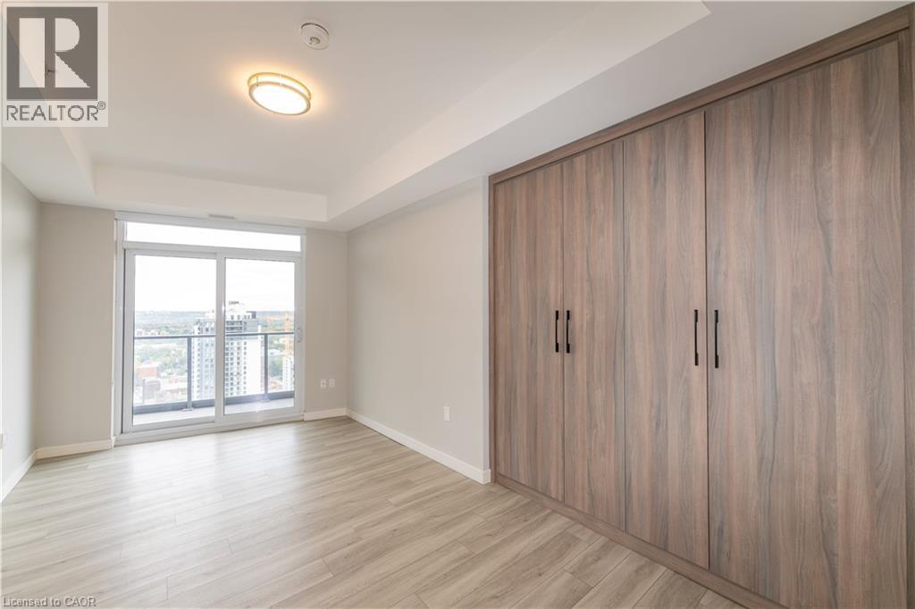 A room with wooden flooring and a large window with a view of buildings outside.