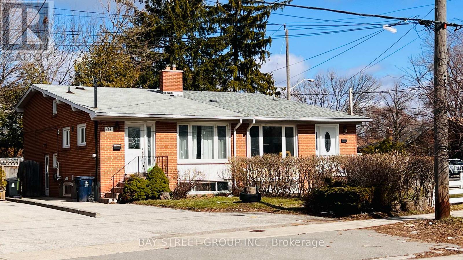 A red brick house with a green roof and a sign that says Bay Street Group Inc., Brokerage.