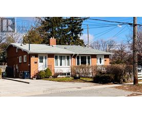 A red brick house with a green roof and a sign that says Bay Street Group Inc., Brokerage.