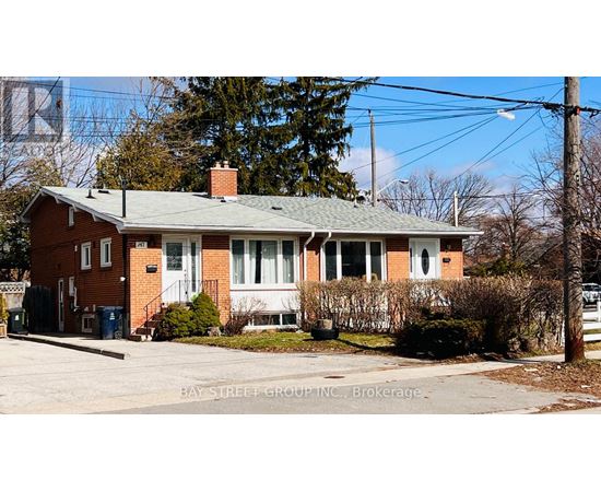 A red brick house with a green roof and a sign that says Bay Street Group Inc., Brokerage.