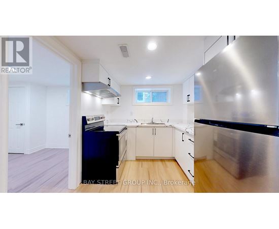 A modern kitchen with a stainless steel refrigerator and wooden flooring.