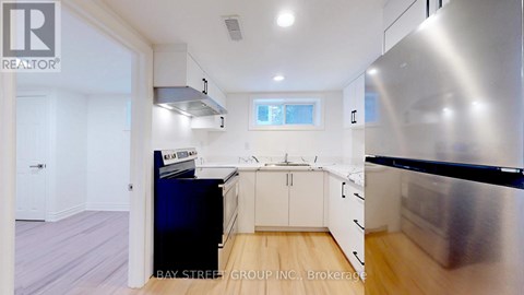 A modern kitchen with a stainless steel refrigerator and wooden flooring.