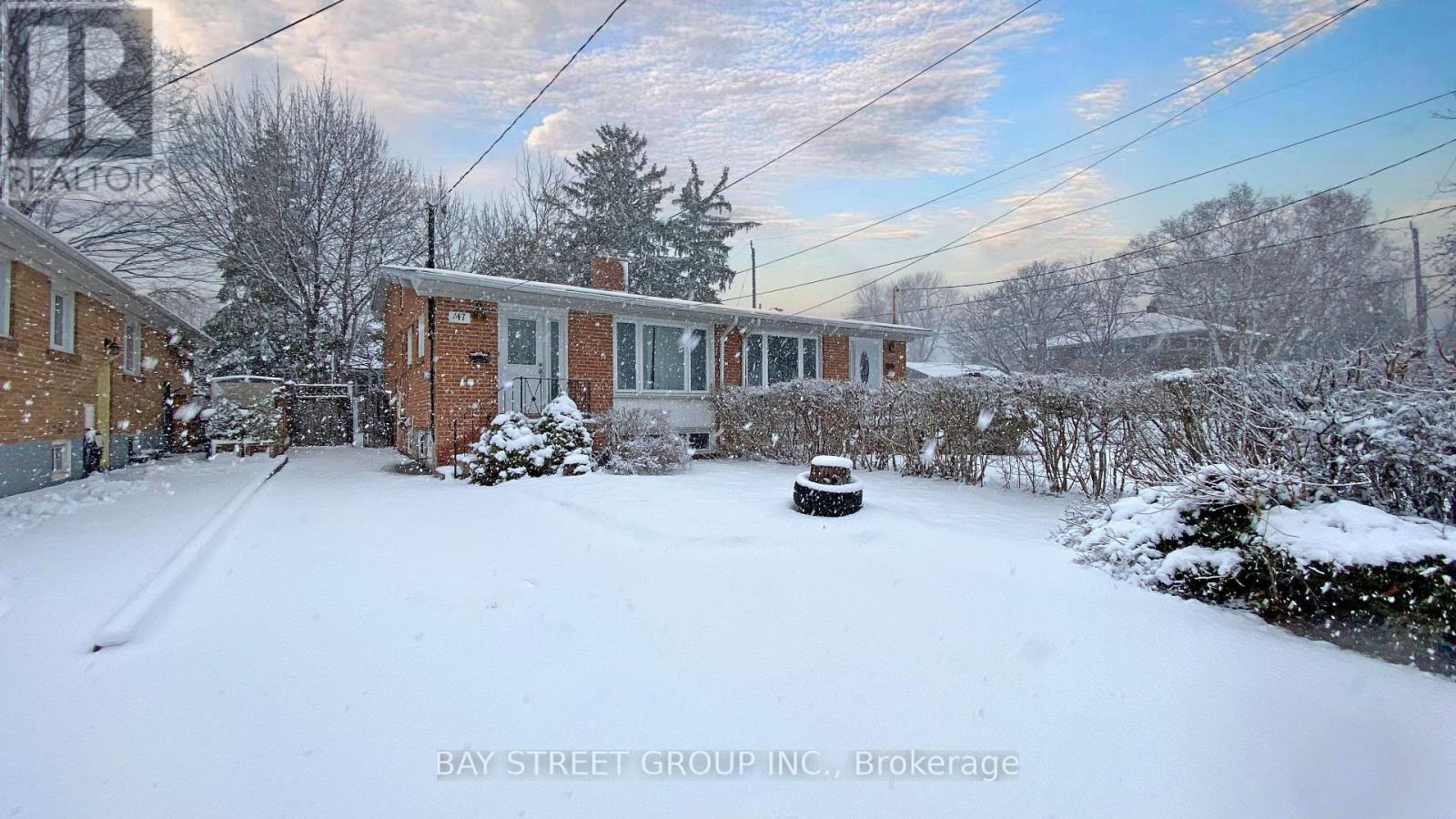A snow-covered yard with a house and trees in the background.