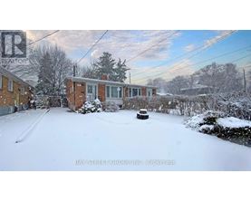 A snow-covered yard with a house and trees in the background.