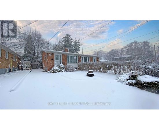 A snow-covered yard with a house and trees in the background.