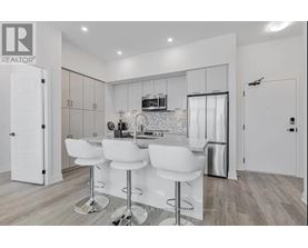 A modern kitchen with white chairs and a bar stool.