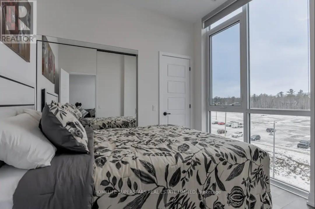 A bedroom with a large bed and a view of a parking lot outside.