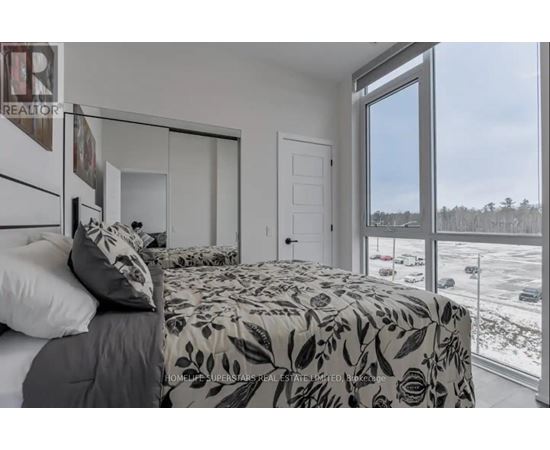 A bedroom with a large bed and a view of a parking lot outside.