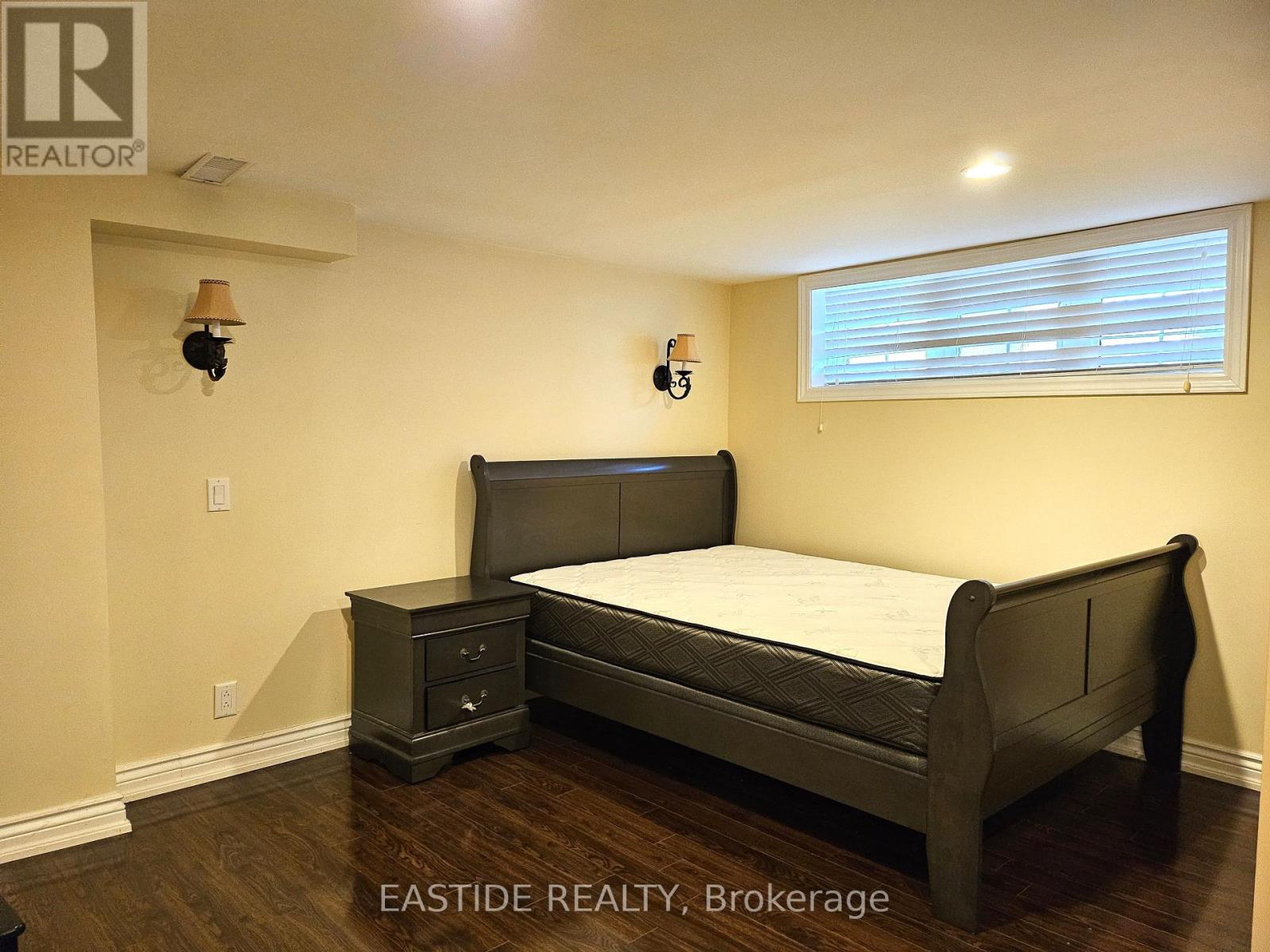 A bedroom with a bed, nightstand, and window.