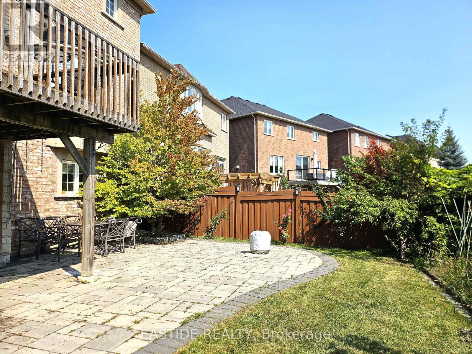A patio area with a table and chairs is surrounded by a wooden fence and houses.