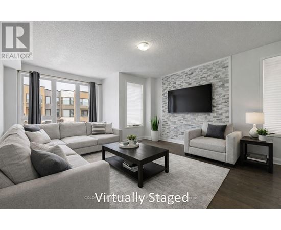 A living room with a grey couch, a black coffee table, a white chair, and a stone wall with a flat screen TV mounted on it.