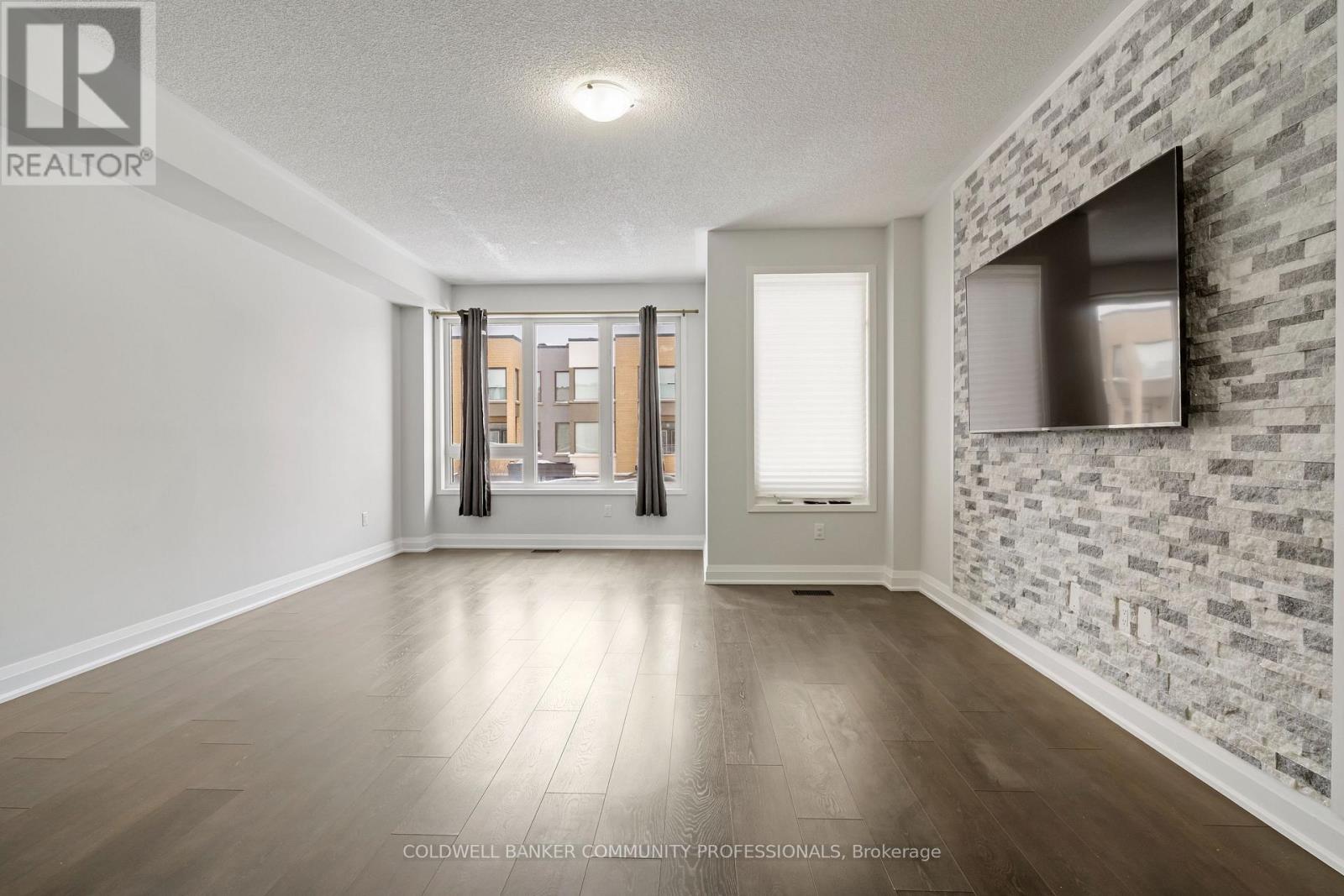 A spacious room with a brick wall and a sliding glass door leading to a balcony.