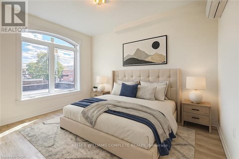 A bedroom with a large bed, a nightstand, and a window with a view of the city.