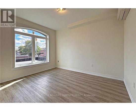 A room with a large window and wooden flooring.