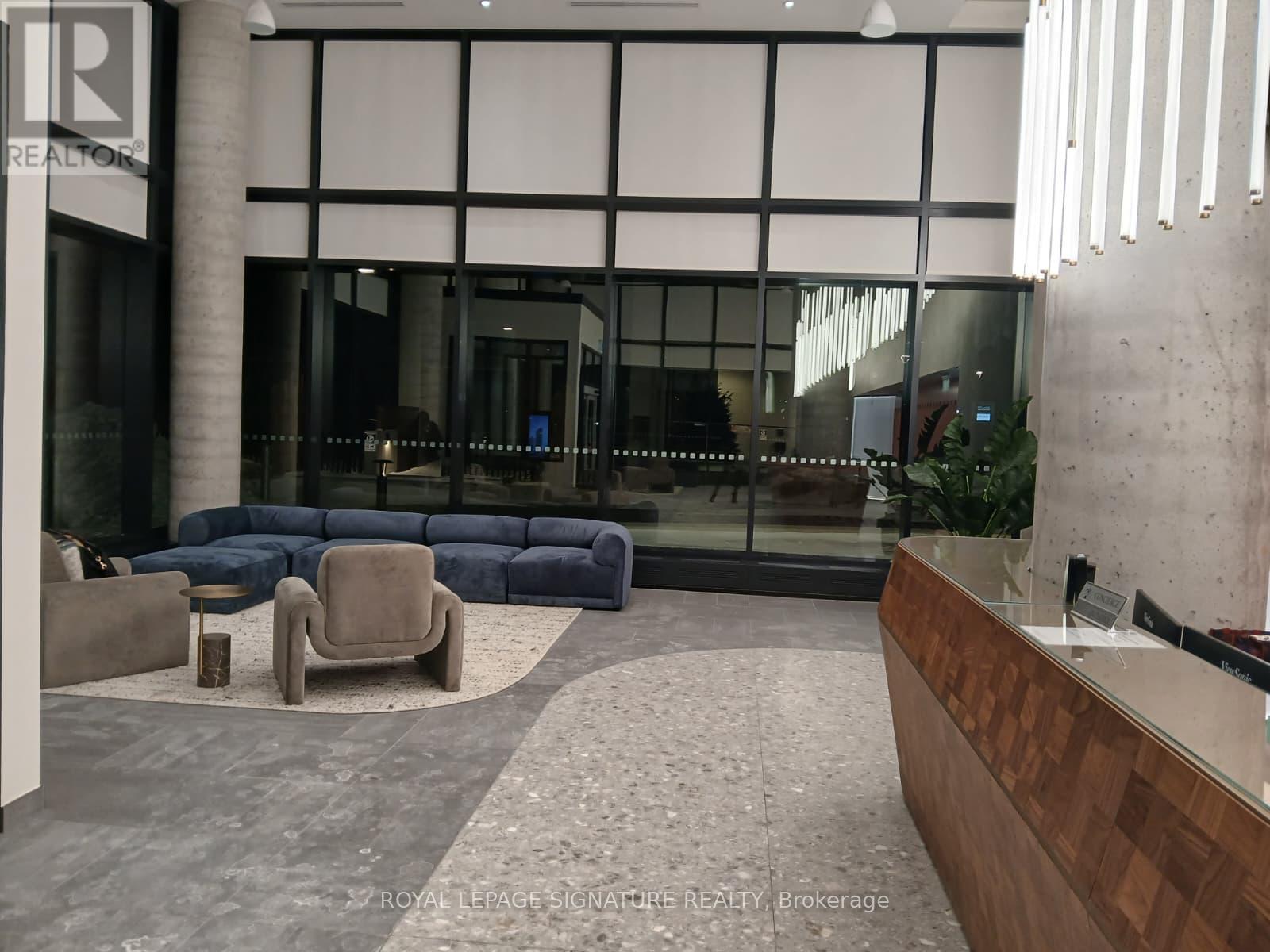 A modern office lobby with a reception desk and a blue sofa.