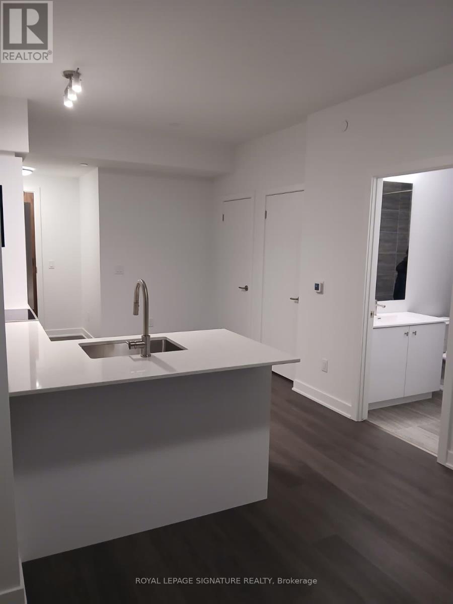 A white kitchen with a sink and a brokerage sign.