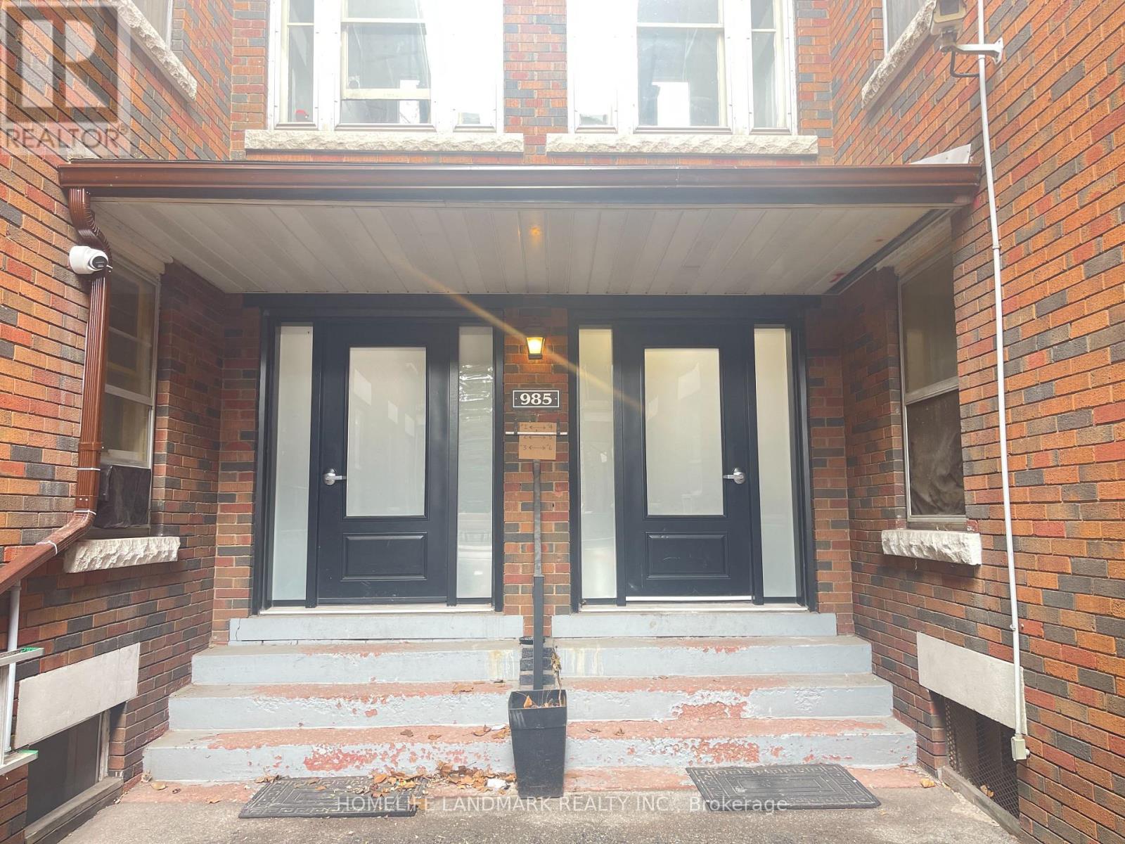 A brick building with a black door and a sign that says REALTOR.