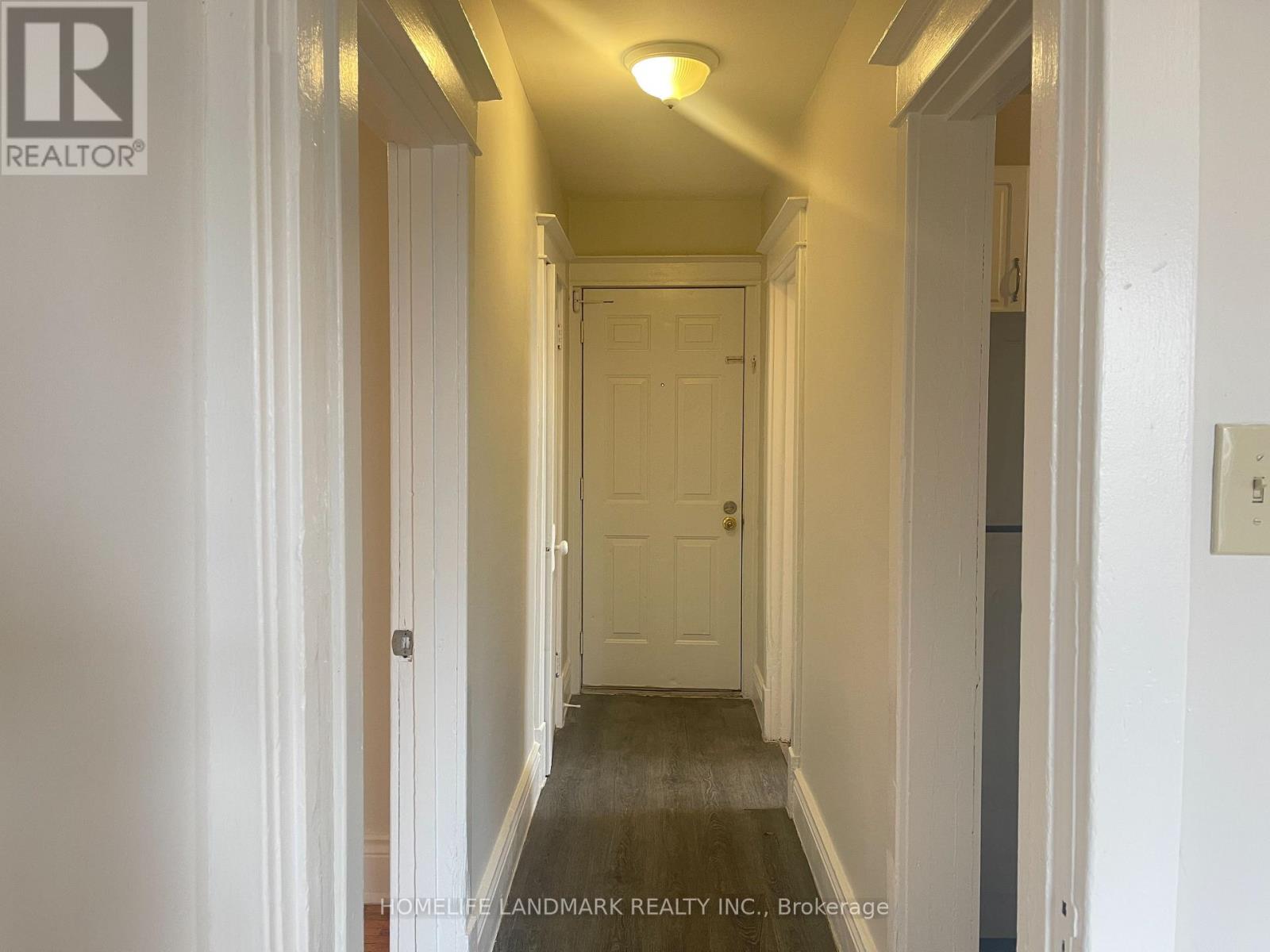 A hallway with a door at the end and a light on the ceiling.