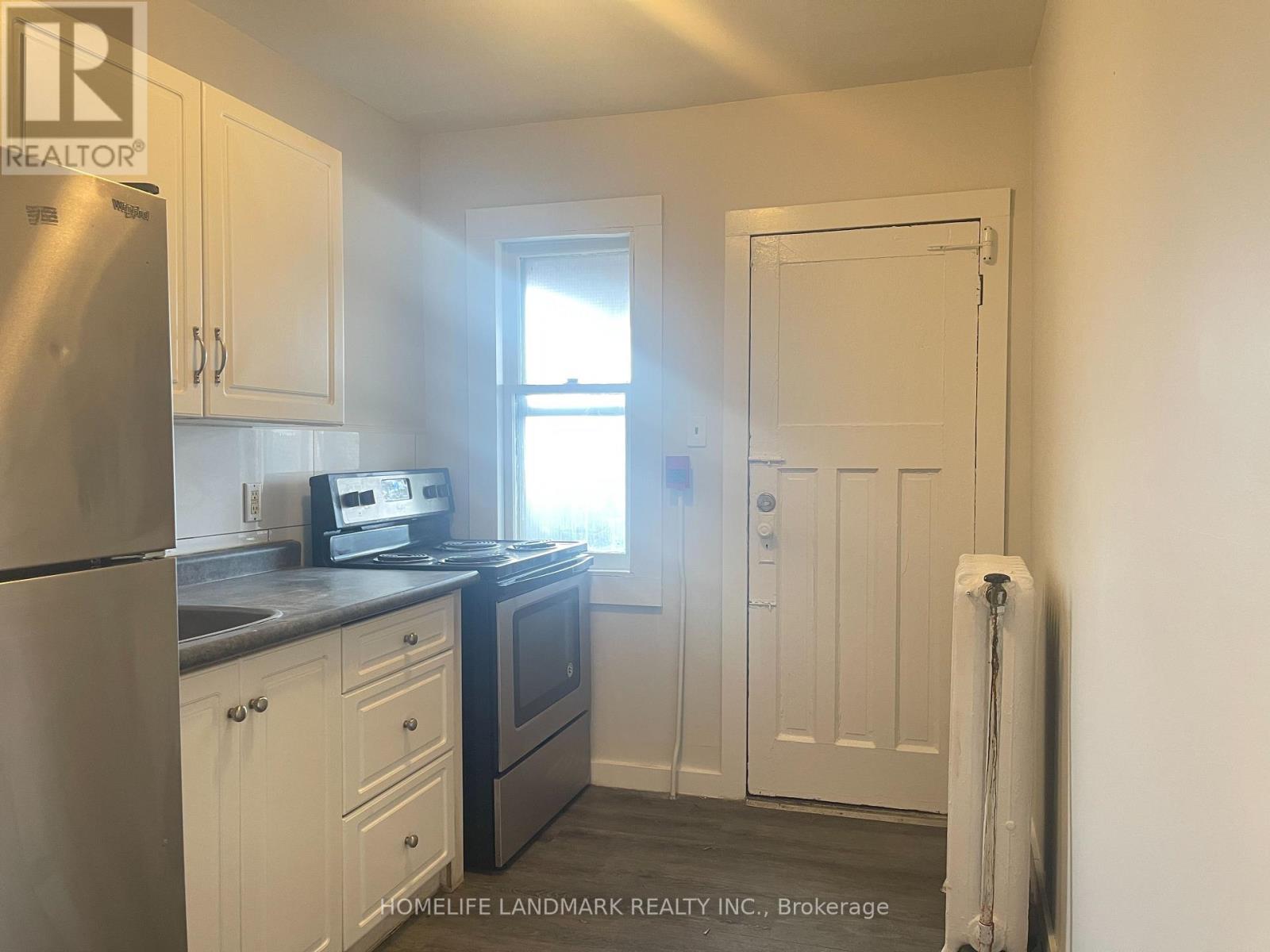 A small kitchen with white cabinets and a stainless steel refrigerator.