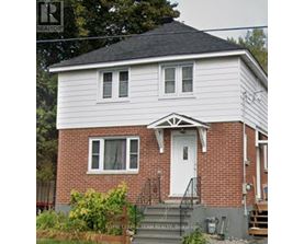A white house with a red brick chimney is for sale.