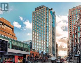 A city street with a large building in the middle and cars parked on the side.