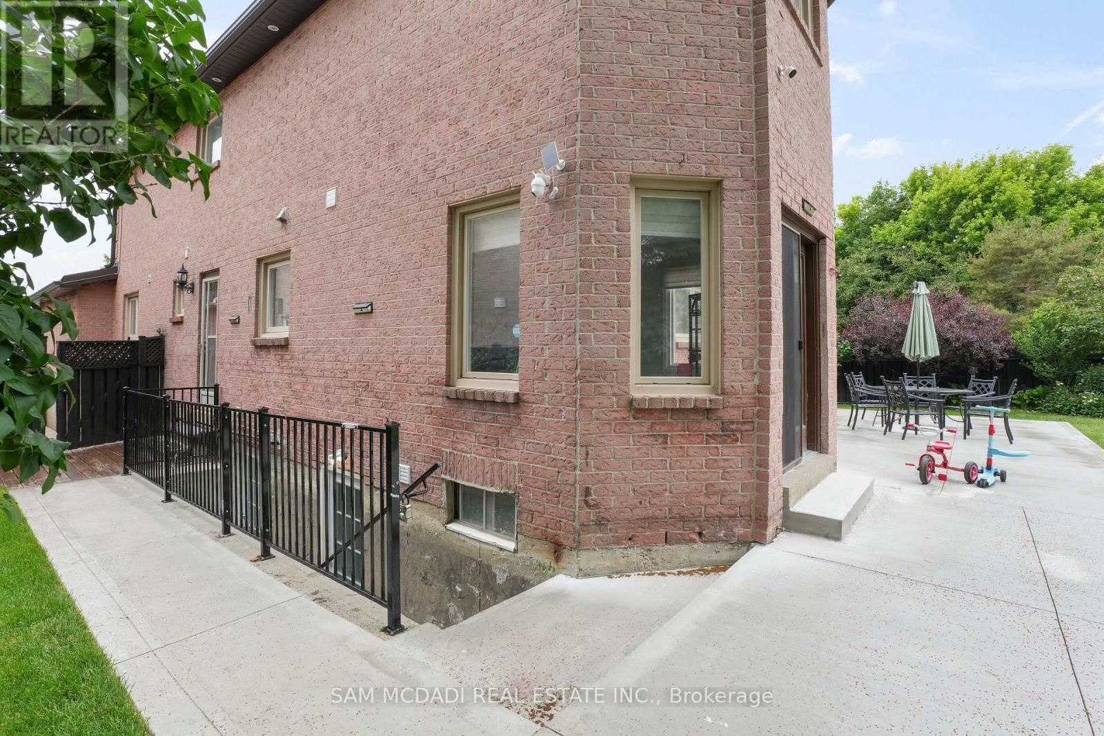 A red brick house with a black fence in front.