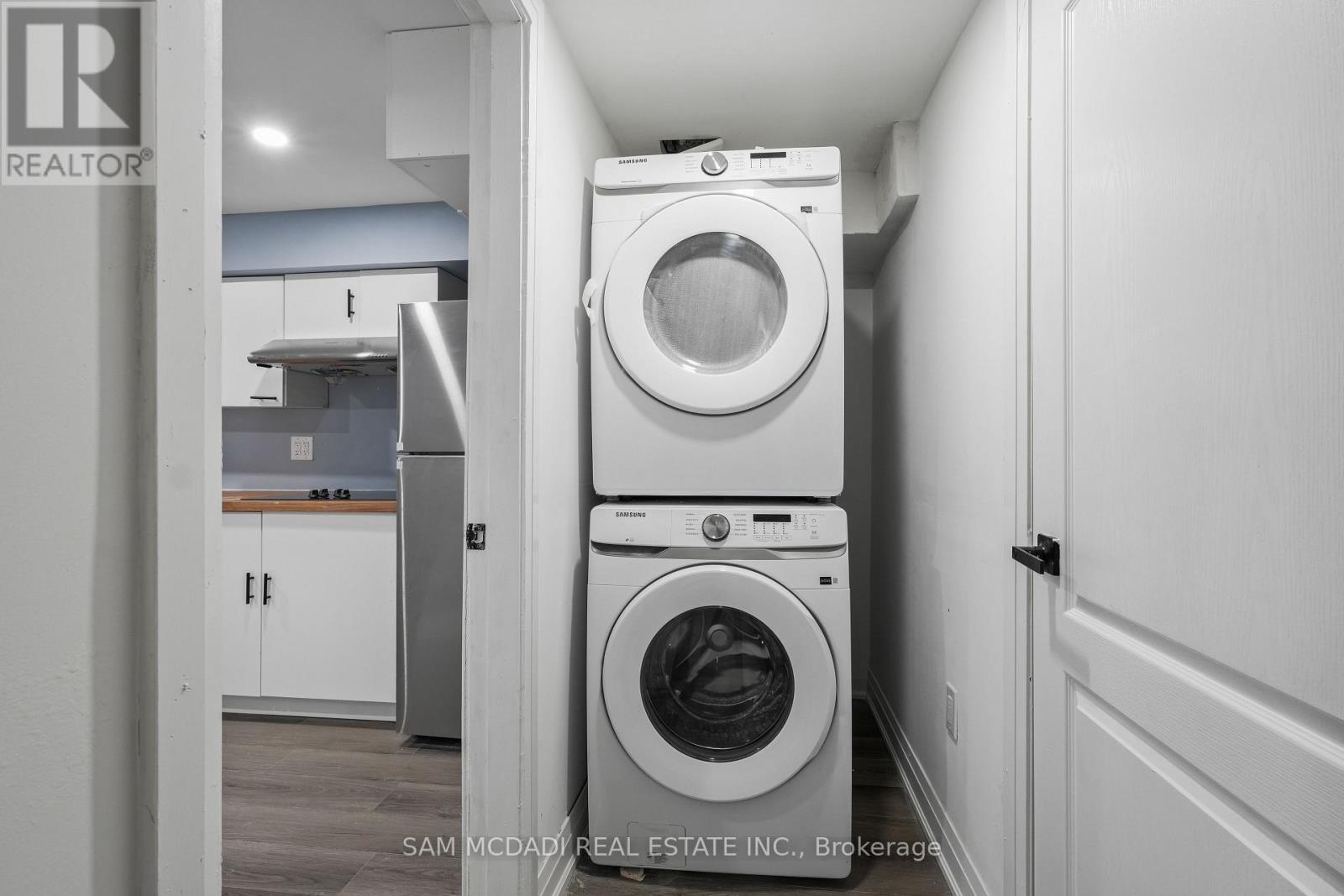 A white washing machine is stacked on top of another white washing machine in a small laundry room.