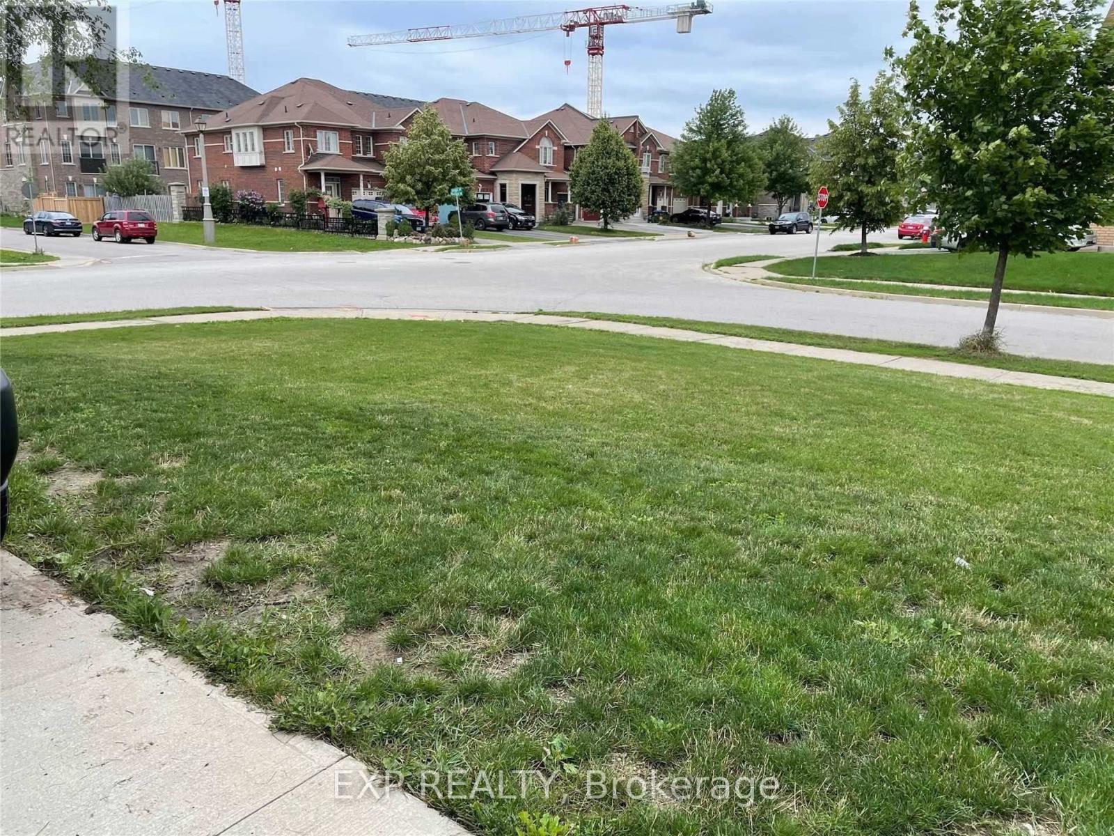 A grassy area in front of a row of houses with a crane in the background.
