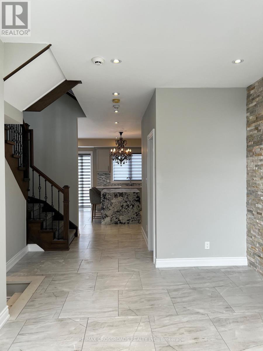 A spacious hallway with a staircase and a chandelier.
