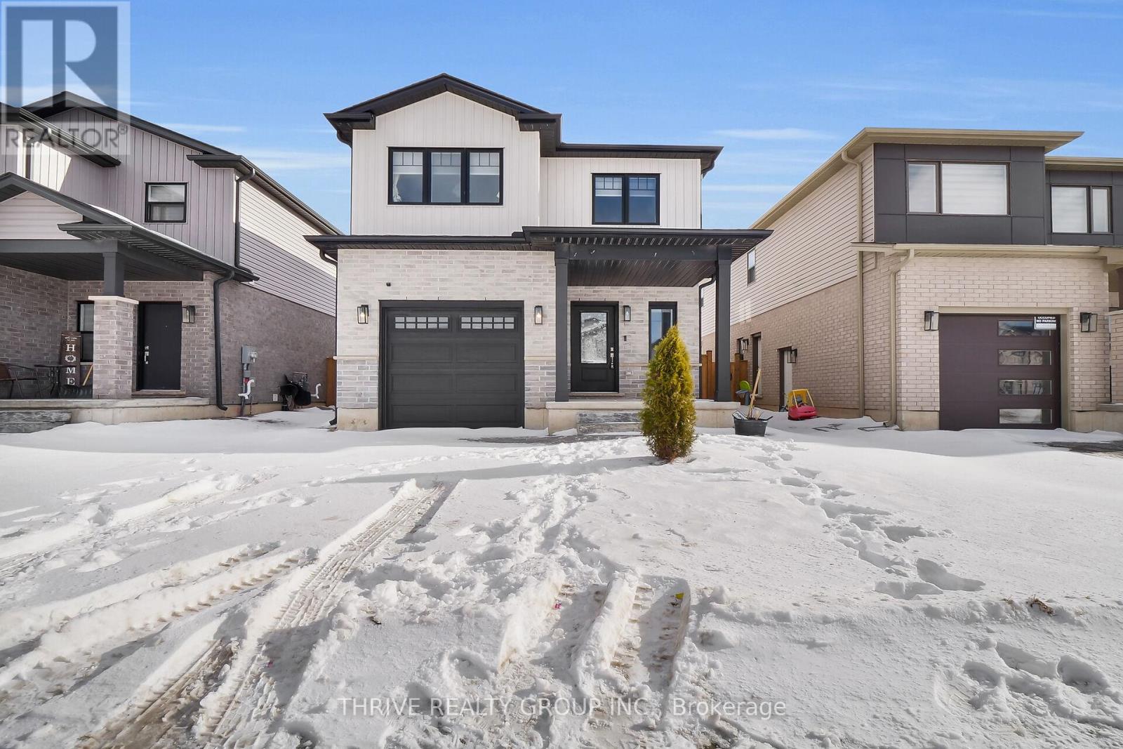 A real estate brokerage sign is displayed on a building in a snowy lot.