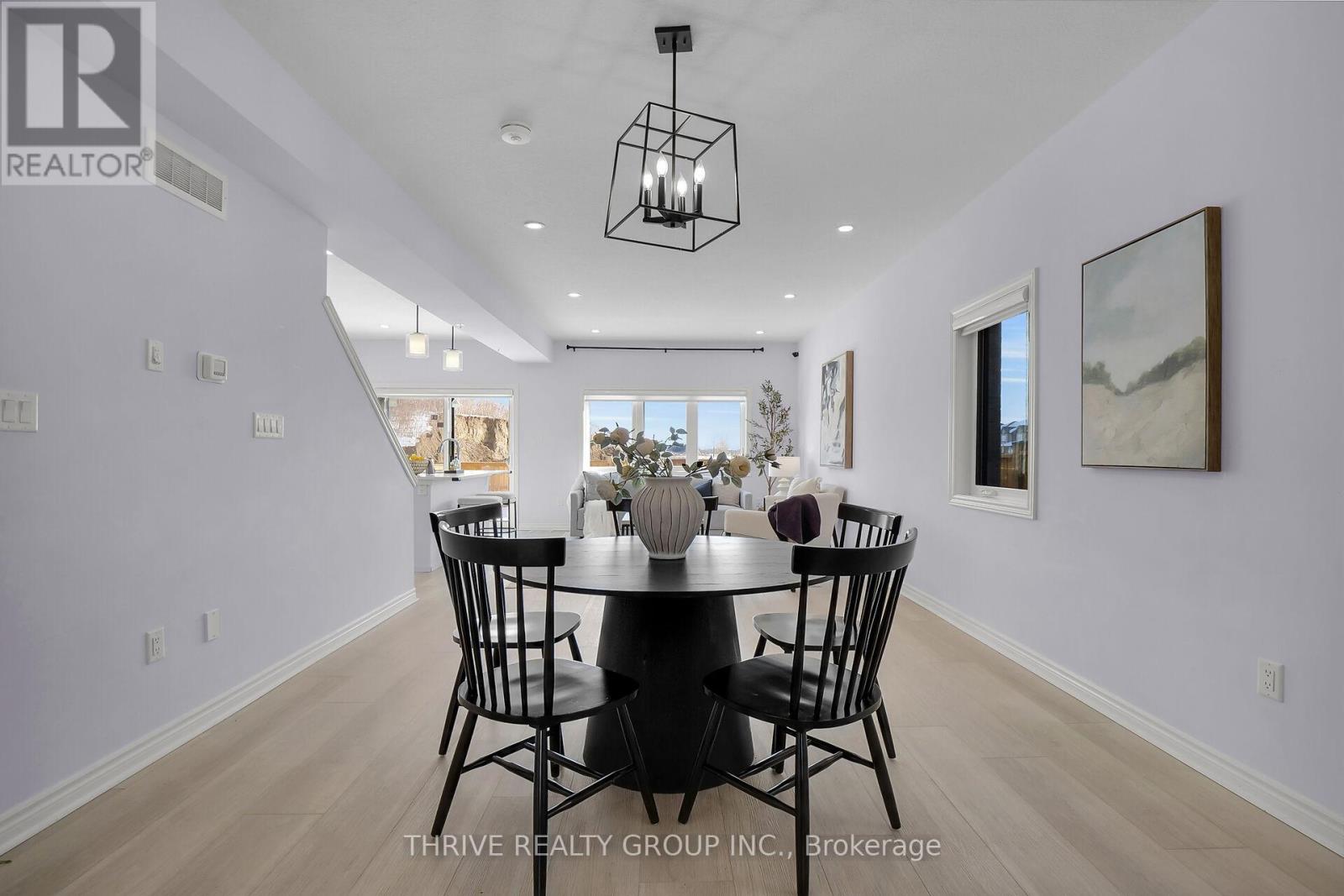 A dining room with a table set for four and a view of the kitchen through the window.