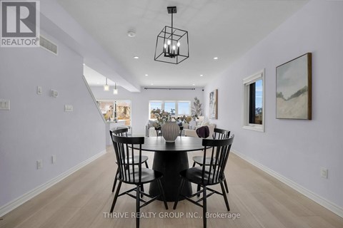 A dining room with a table set for four and a view of the kitchen through the window.